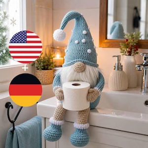May include: A crochet gnome figurine featuring a tall, light blue pointed hat adorned with small white pom-poms, a beige nose, a long white faux fur beard, and light blue crochet arms and legs, holding a roll of white toilet paper.