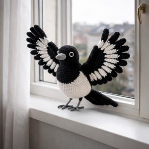 Peut inclure: Un geai crocheté, principalement noir et blanc, avec les ailes déployées. L'oiseau est posé sur un rebord de fenêtre, avec un bec et un œil détaillés. Cet article fait main est une pièce décorative.
