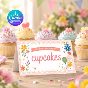 May include: A rectangular folded card with a scalloped edge and a light pink gingham pattern. The card features floral illustrations, two balloons, and the text "IT'S FUN TO BE ONE" above the word "cupcakes" written in a large pink script font.