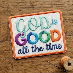 May include: Embroidered patch with the words "GOD is GOOD all the time" in teal, purple, blue, green, and orange. The patch has an orange border and is on a white background. A needle and thread spool are in the background.