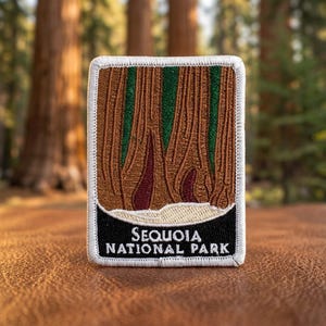 May include: Embroidered patch featuring a detailed illustration of Sequoia trees with brown, green, and burgundy tones. The patch has a white border and a black base with the text "SEQUOIA NATIONAL PARK".