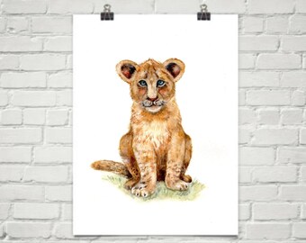 May include: A watercolor painting of a light brown lion cub sitting on a green patch of grass. The cub has blue eyes and a light brown mane.