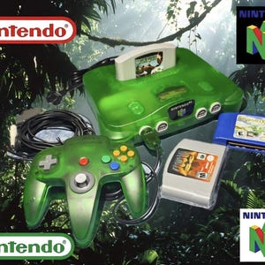 Può includere: Una console di gioco Nintendo 64 verde trasparente con un controller abbinato e tre cartucce di gioco. Il logo Nintendo è visibile. La console e il controller hanno una finitura verde traslucida.