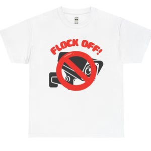 May include: A white short-sleeve t-shirt featuring a graphic of a black security camera with a red prohibition circle over it. Above the camera, the text FLOCK OFF! is printed in bold red capital letters. The design is centered on the chest.