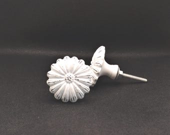 May include: Two white daisy-shaped cabinet knobs with a distressed finish. The knobs have a detailed floral design and a metal screw for installation. The knobs are likely used for furniture or decorative purposes.