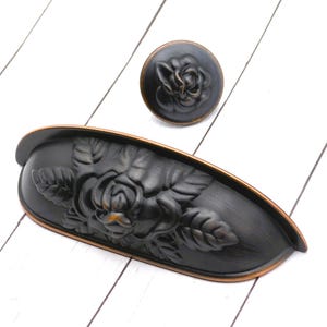 May include: A white ceramic mug with a black handle and the text "But First, Coffee" in a bold, black font. The mug is set against a blurred background, highlighting its simple design.