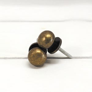 May include: A white ceramic mug with a black handle and the text "But First, Coffee" in a bold, black font. The mug is set against a blurred background, suggesting a cozy setting.