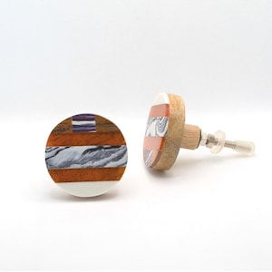 May include: A white ceramic mug with a black handle and the text "But First, Coffee" in a black, bold font. The mug is sitting on a wooden surface. The mug is approximately 4 inches tall.