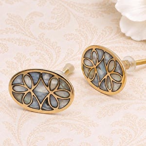 May include: Two oval-shaped cabinet knobs featuring a gold-toned metal frame with an intricate lattice pattern. The interior of each knob is inlaid with iridescent, multi-colored mother-of-pearl segments. Each knob includes a threaded metal bolt.
