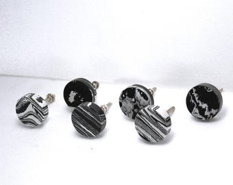 May include: Six round cabinet knobs with a black and white marbled design. The knobs have a silver-colored screw post. The knobs are made of a solid material and are suitable for drawers or cabinets.