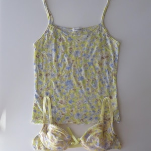 May include: A yellow camisole with thin straps and a blue and white floral pattern paired with a matching underwire bra featuring the same floral print, a small yellow center bow, and adjustable shoulder straps on a plain white background.