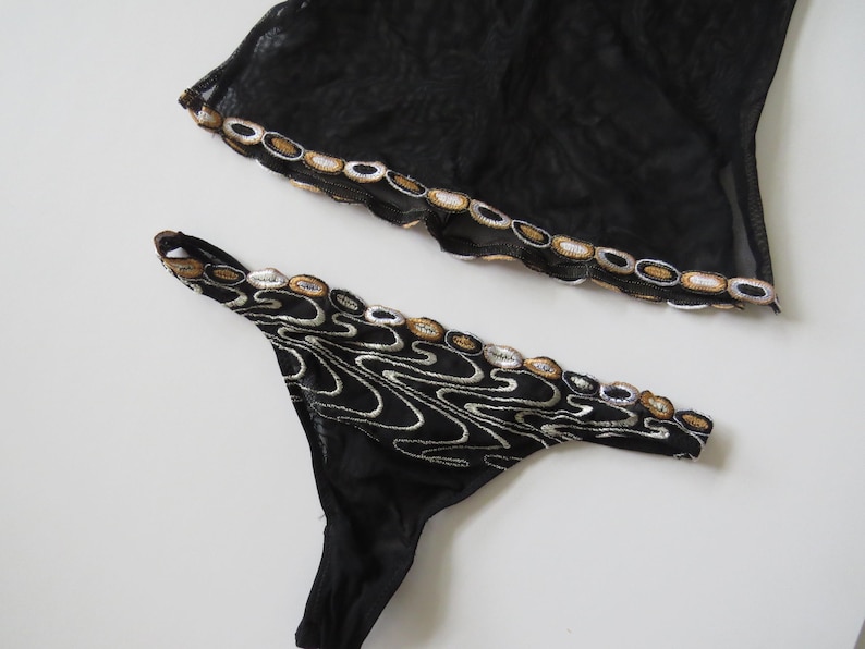 Puede incluir: Una taza de cer&aacute;mica blanca con un asa negra y el texto "But First, Coffee" en negro y negrita. La taza est&aacute; sobre una superficie blanca. La taza mide aproximadamente 10 cm de alto.