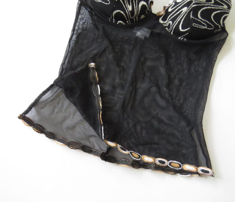 Puede incluir: Una taza de cer&aacute;mica blanca con asa negra y el texto "But First, Coffee" en negrita negra. La taza se encuentra sobre un fondo borroso, sugiriendo un ambiente acogedor.