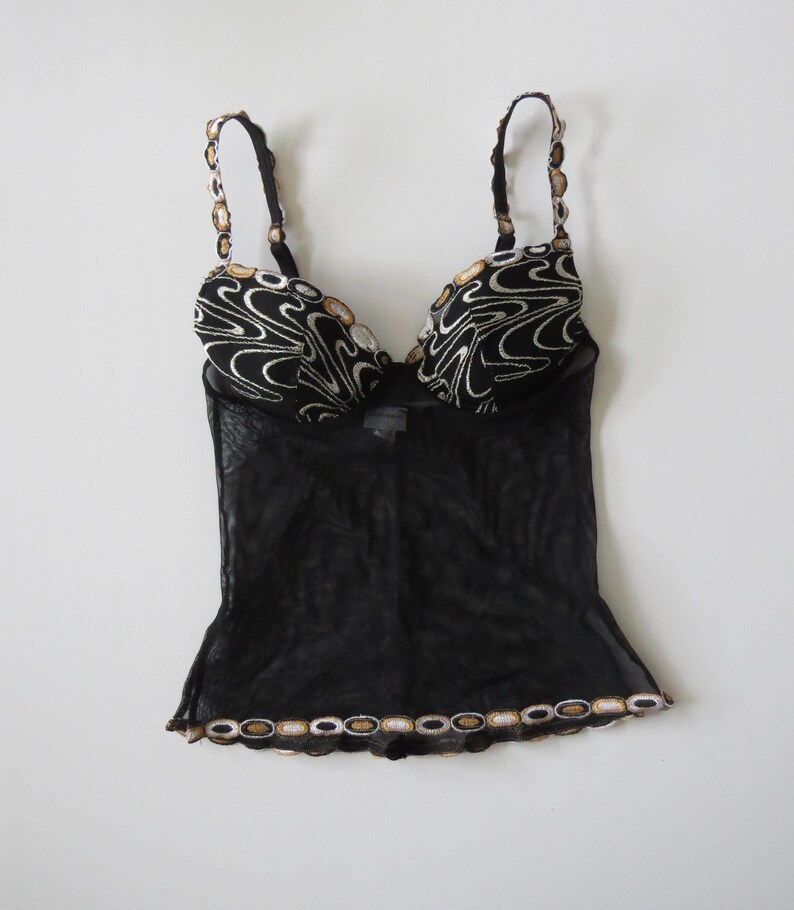 Puede incluir: Una taza de cer&aacute;mica blanca con un asa negra y el texto "But First, Coffee" en negro, con una fuente de estilo manuscrito. La taza est&aacute; sobre una superficie blanca.