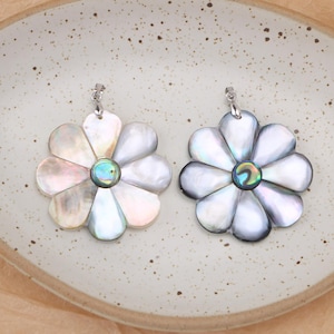 May include: Two flower-shaped pendants crafted from iridescent shell material. Each pendant features eight rounded petals surrounding a central circular inlay with a vibrant, multi-colored abalone-like finish and a silver-toned metal bail.