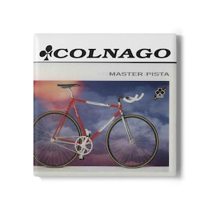 Könnte beinhalten: Eine quadratische Dekofliese mit einer Grafik eines rot-weißen Colnago Master Pista Fahrrads. Oben sind das schwarze Colnago-Logo und der Schriftzug zu sehen. Der Hintergrund zeigt einen Sonnenuntergang mit Wolken. Ein kleines Kleeblatt-Emblem ist rechts.