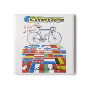 May include: A square white tile featuring a blue road bicycle illustration. The text reads Gitane, la bicyclette de France, and Championne du Monde. Below the bicycle is a grid of various international flags in red, blue, yellow, and green.