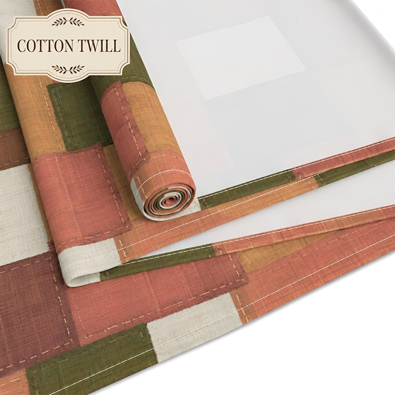 K&ouml;nnte beinhalten: Ein Baumwoll-Twill-Stoff mit einem Patchwork-Design aus rechteckigen Bl&ouml;cken in Olivgr&uuml;n, Terrakotta-Orange und Off-White. Das Textil ist teilweise aufgerollt und zeigt eine wei&szlig;e Unterseite sowie sichtbare N&auml;hte entlang der Kanten.