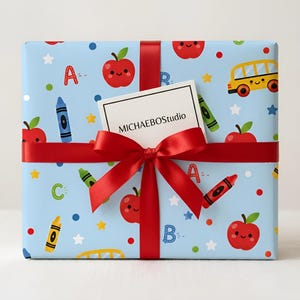 May include: A present wrapped in light blue paper decorated with a school-themed pattern of apples, crayons, stars, and a yellow school bus. It's tied with a red ribbon and bow, with a small card that reads "MICHAELBOStudio".
