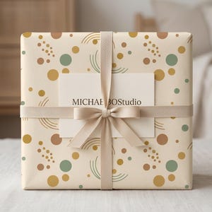 May include: A gift wrapped in patterned paper with a cream background, featuring brown, green, and gold circles and curved lines. A cream ribbon and bow secure a white card with the text "MICHAEL BOStudio".