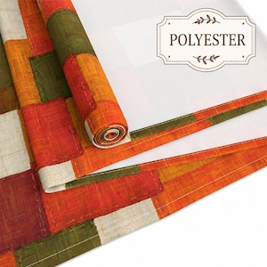 K&ouml;nnte beinhalten: Eine Stoffrolle und ein flaches Textilst&uuml;ck mit einem Patchwork-Muster aus rechteckigen Bl&ouml;cken in Orange, Olivgr&uuml;n, Rot und Creme. Der Stoff hat eine sichtbare Webstruktur und enth&auml;lt ein Etikett mit dem Text POLYESTER.