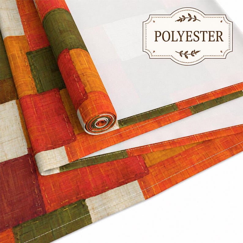 K&ouml;nnte beinhalten: Eine Stoffrolle und ein flaches Textilst&uuml;ck mit einem Patchwork-Muster aus rechteckigen Bl&ouml;cken in Orange, Olivgr&uuml;n, Rot und Creme. Der Stoff hat eine sichtbare Webstruktur und enth&auml;lt ein Etikett mit dem Text POLYESTER.