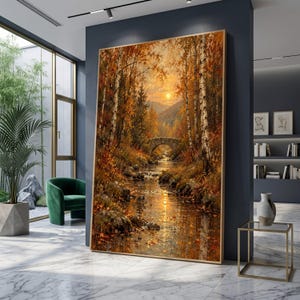 Puede incluir: Un gran cuadro rectangular de pared que representa una escena de bosque otoñal con un puente de piedra sobre un arroyo, con luz solar dorada filtrándose a través de abedules con follaje naranja y marrón, enmarcado en madera clara.