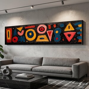 Könnte beinhalten: Abstraktes Kunstwerk mit schwarzem Rahmen. Das Kunstwerk zeigt farbenfrohe geometrische Formen in Rot, Gelb, Blau und Rosa vor einem schwarzen Hintergrund. Die Formen umfassen Kreise, Dreiecke und Rechtecke. Das Gemälde hängt über einem grauen Sofa.