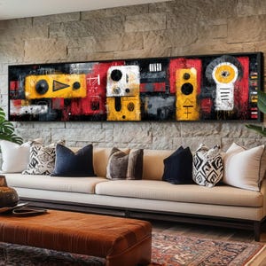 Könnte beinhalten: Abstraktes Kunstwerk in einem schwarzen Rahmen. Das Kunstwerk zeigt geometrische Formen in Gelb, Rot, Weiß und Schwarz. Das Gemälde hängt über einem beigen Sofa mit dekorativen Kissen. Der Raum hat eine Steinmauer.