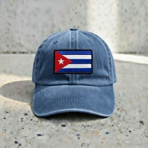 May include: A blue baseball cap with a Cuban flag patch. The flag features a red triangle with a white star, and blue and white stripes. The cap is made of a soft material and has a curved brim.
