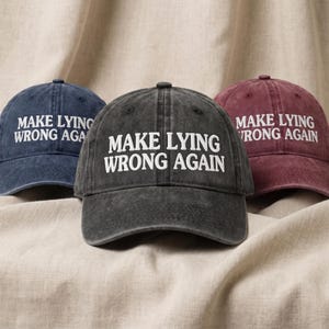 May include: Three baseball caps in navy blue, charcoal gray, and maroon, each featuring a distressed fabric finish. The front of every cap is embroidered with the white text "MAKE LYING WRONG AGAIN" in a bold, capitalized, sans-serif font style.