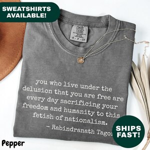 May include: A grey t-shirt featuring a quote by Rabindranath Tagore. The text reads "you who live under the delusion that you are free are every day sacrificing your freedom and humanity to this fetish of nationalism."