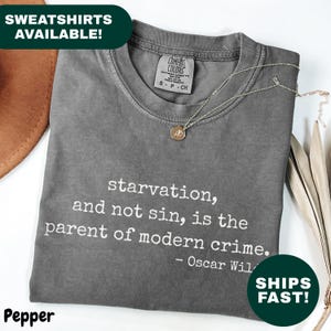 May include: A gray t-shirt with the quote "starvation, and not sin, is the parent of modern crime." by Oscar Wilde. The shirt has a crew neck and a small pendant necklace. The word "Pepper" is at the bottom left.