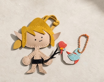 May include: A leather keychain featuring a stylized elf figure with yellow hair, pointed ears, and a black belt, holding a black twig. Beside it is a smaller leather keychain shaped like a rooster with white, light blue, and red accents on an orange ball chain.