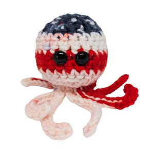 Op de afbeelding: Een gehaakt octopus speelgoed met een rood, wit en blauw kleurenschema. De octopus heeft zwarte knoopogen en rode tentakels. De tekst "Sir Wiggleton the Unraveled" staat in de afbeelding.