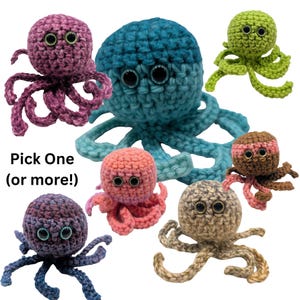 Op de afbeelding: Een verzameling handgemaakte gehaakte octopus speelgoed in verschillende kleuren, waaronder paars, blauw, groen, roze, bruin en bruin. Elke octopus heeft grote, wiebelende ogen en gekrulde tentakels. De tekst "Pick One (or more!)" wordt weergegeven.