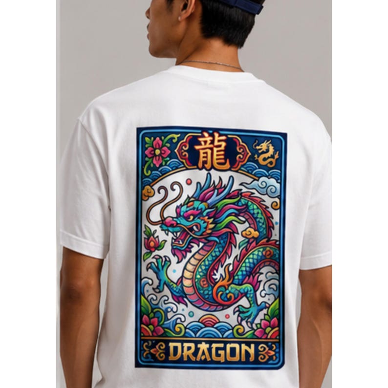 May include: White t-shirt featuring a colorful dragon design on the back. The dragon is depicted in shades of blue, green, and red, with the word "DRAGON" below. The design is framed by a blue border with floral and wave motifs.