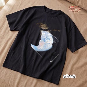 May include: Black t-shirt featuring a graphic design of a person's silhouette with the Earth visible within a geometric shape. The shirt has short sleeves and a crew neck. The word "black" is printed on the bottom right corner.