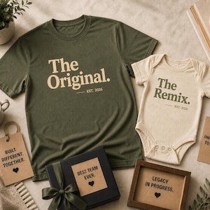 Może przedstawiać: Oliwkowozielony t-shirt z napisem The Original. EST. 2026 oraz kremowe body dziecięce z napisem The Remix. EST. 2026. Zestaw zawiera zawieszki prezentowe z frazami Built Different. Together., From One Generation To The Next. oraz Legacy In Progress.