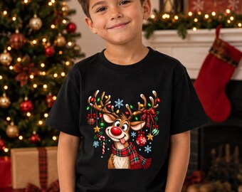 Puede incluir: Una camiseta negra de manga corta con un gráfico de un reno de nariz roja, que lleva una bufanda de cuadros y está decorado con adornos navideños coloridos, luces y copos de nieve colgando de sus astas en la parte frontal.
