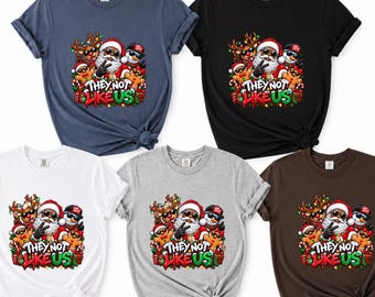 Puede incluir: Cinco camisetas de manga corta y cuello redondo en azul marino, negro, blanco, gris y marrón. Cada camiseta presenta un gráfico de Santa Claus, un reno, un muñeco de nieve y dos galletas de jengibre con el texto "THEY NOT LIKE US".