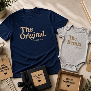 Może przedstawiać: Granatowa koszulka z napisem The Original. EST. 2026 w kolorze opalenizny oraz szare body niemowlęce z napisem The Remix. EST. 2026 w kolorze opalenizny. Zestaw zawiera zawieszki prezentowe z tekstami, w tym Built Different. Together. oraz From One Generation To The Next.