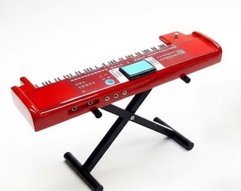 May include: A bright red electronic keyboard with a black stand. The keyboard has a small blue screen and multiple buttons and keys. The stand is a black, X-shaped design, providing support. The keyboard is set against a white background.