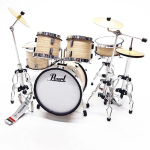 Op de afbeelding: Miniatuur drumstel met natuurlijk houten drums, zilveren hardware en goudkleurige bekkens. Het "Pearl" logo staat op de grote trom. De set bevat een bastrommel, snaredrum, toms en bekkens.