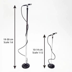 Puede incluir: Dos soportes de micrófono en miniatura, uno de 19-30 cm de alto (escala 1:6) y el otro de 10-14 cm de alto (escala 1:12). Ambos tienen un poste plateado, base negra y un micrófono. Sobre fondo blanco.