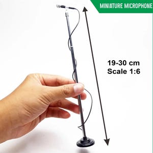 May include: A miniature microphone on a stand, with a black cable. The stand is silver and black, and the microphone is black and silver. The text "MINIATURE MICROPHONE" is in a green box. The stand measures 7.5-11.8 inches. Scale 1:6.