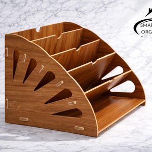 May include: A wooden desk organizer with multiple compartments and a sloped design. The organizer has a natural wood grain finish and decorative cutouts on the side. The logo "Smartspace Organizer" is visible.
