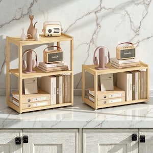 May include: Two light-coloured wooden shelves with three tiers each, displaying books, small radios, headphones, and decorative items. The shelves are set against a marble-patterned wall.