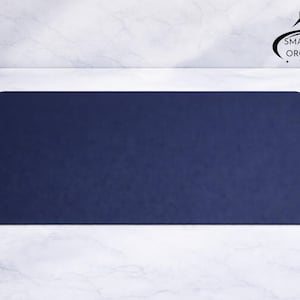 Può includere: Un tappetino da scrivania rettangolare blu navy con angoli arrotondati. Il tappetino è realizzato in un materiale liscio ed è progettato per proteggere la superficie della scrivania. Il logo Smartspace Organizer si trova nell'angolo in alto a destra.