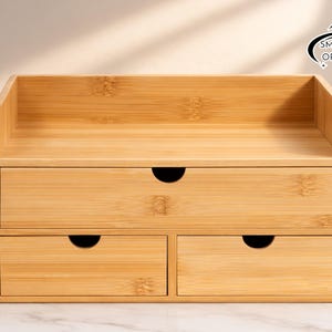 May include: A bamboo desk organizer with three drawers and a top shelf. The organizer has a natural wood finish and a curved design on the drawer pulls. The Smartspace Organizer logo is visible in the upper right corner.